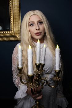 a woman with long blonde hair is holding a candelabra