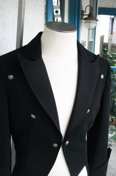 A classic dress coat with gothic detailing. This piece has peak lapels and a curved upper collar so that the points overlap. The fronts of the tailcoat just kiss and finish with a hook and eye. The unique pointed cuffs feature 6 buttons. And the back tightens with a belt. The piece is made from a gorgeous 12oz wool suiting. ----------------------------------- We can make a tailcoat in any style. From steampunk, to Regency, to stunning white tie. Contact us with the details that you would like be Gothic Formal Outerwear For Fall, Formal Gothic Outerwear For Fall, Gothic Formal Winter Outerwear, Victorian Black Formal Outerwear, Steampunk Long Sleeve Formal Outerwear, Victorian Style Formal Long Coat, Gothic Black Outerwear For Formal Occasions, Black Gothic Outerwear For Formal Occasions, Elegant Fitted Outerwear For Cosplay