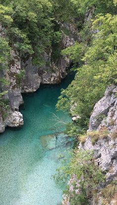 the water is crystal blue and clear in this river that runs between two cliffs with trees on both sides