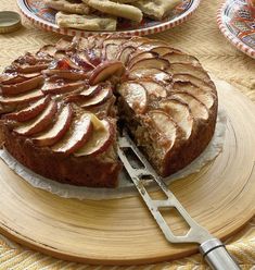 an apple cake with slices cut out on a wooden plate next to crackers and cookies