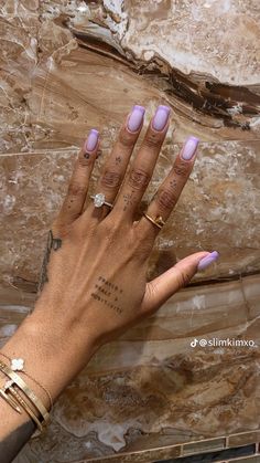 a woman's hand with purple nail polish and gold bracelets on her wrist