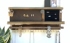 a wooden shelf with jewelry hanging from it's sides and a plant in the background