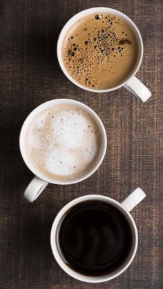 two cups of coffee sitting on top of a wooden table