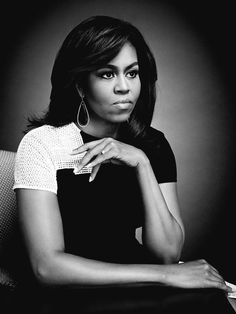 a black and white photo of a woman with her hand on her chin, looking at the camera