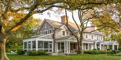 a large white house sitting in the middle of a lush green field with lots of trees