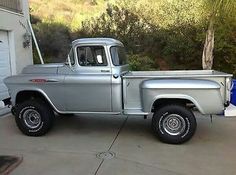 an old silver truck parked in front of a garage