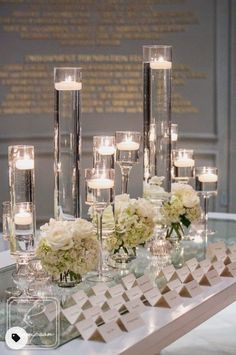 a table topped with lots of candles and vases filled with flowers next to each other