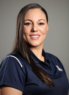 a woman in a polo shirt posing for a photo with her hands on her hips