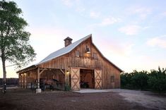 a barn with a horse in the front yard at sunset or dawn, on a farm