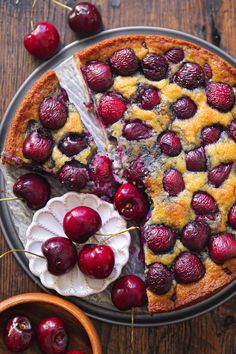 a cherry pie with one slice cut out and cherries on the side