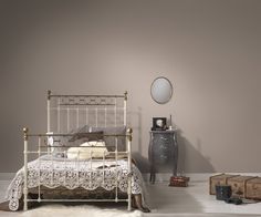 a white bed sitting next to a wooden dresser and mirror on top of a wall