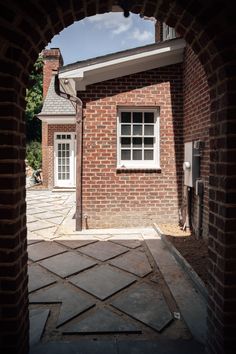 an open door leading to a brick building with a white window on the right side