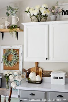 a kitchen with white cabinets and wreaths on the wall over the stove top area