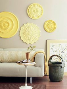 a living room with white furniture and yellow plates on the wall above it's coffee table