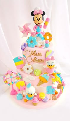 a pink cake with mickey mouse on top and lots of toys around the bottom,