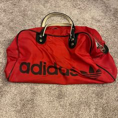 Some Spots Please See Photos, The Adidas Duffle Bag In A Striking Red And Black Color Combination, Accentuated With Leather Details On The Straps. This Bag Is Not Only Visually Appealing But Functional. With Its Spacious Interior, It's Perfect For Everyday Use Or For Those Occasional Trips To The Gym. While It Does Show Some Signs Of Its Journey Through Time, And Minor Wear On The Leather Straps,It Still Retains Its Overall Charm. These Bags Are Rare Finds. Don't Miss Out On The Opportunity To Own This Unique Piece Of Sportswear History And Make A Bold Statement Wherever You Go. Approximate Measurements Below: Length: 47cm Height: 31cm Depth: 23.5cm Adidas Duffle Bag, Black Color Combination, Adidas Bags, Adidas Vintage, Red Adidas, Vintage Adidas, Duffel Bag, Color Combination, Red And Black