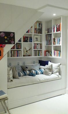 a living room with bookshelves and a couch under the stairs in front of it