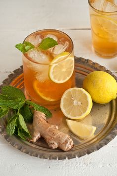 a plate with lemons, ginger and mint on it next to two glasses of water