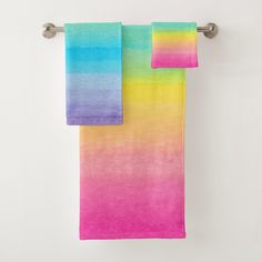 two towels hanging on a towel rack in front of a white wall with the colors of rainbow and blue