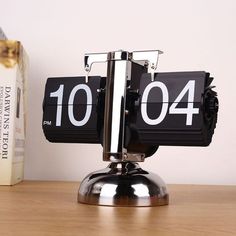 an alarm clock sitting on top of a wooden table next to a bookshelf