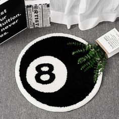 a black and white round rug with the number eight on it next to a book