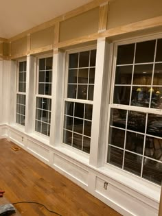 an empty room with wood floors and white trim on the walls, windows are being installed