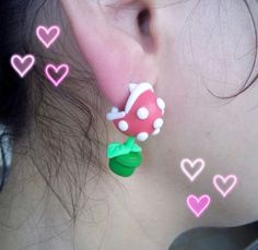 a close up of a person's ear with hearts and a mushroom on it