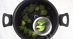 broccoli is being cooked in a pot with a strainer on the side