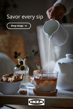 a person pouring tea into a cup on top of a table next to other dishes