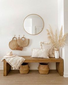 a wooden bench sitting under a mirror in a living room next to pillows and baskets