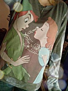 a woman wearing a sweatshirt with an image of princesses on it