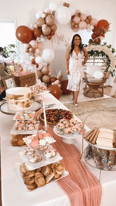 a woman standing in front of a table filled with desserts and pastries on it