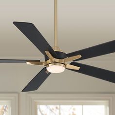 a ceiling fan that is hanging from the ceiling in a room with white walls and windows