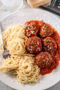 a white plate topped with spaghetti and meatballs next to a slice of toasted bread