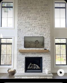 a living room filled with lots of windows and a fire place in the middle of it