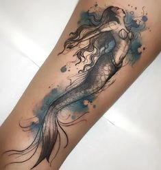 a woman's leg with a tattoo on it that has a watercolor mermaid tail