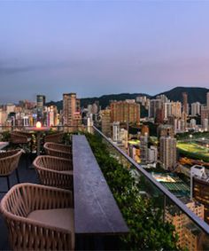 an outdoor dining area with tables and chairs overlooking the cityscape at dusk in hong kong, china