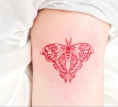 a small red butterfly tattoo on the back of a woman's thigh