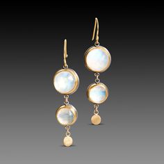 A pair of luminous moonstones are accented with a tiny 22k gold disk in each of these lovely earrings. Set in bezels of 22k gold, and backed with sterling silver. 18k gold earwires. Earrings hang approximately 1 1/2 inches. Matte finish. Gold Moonstone Hand Forged Earrings, Gold Hand Forged Moonstone Earrings, Gold Hand-forged Moonstone Earrings, Hand Forged Gold Moonstone Earrings, Gold Moonstone Earrings With Moon Phase Detail, Moonstone Round Yellow Gold Earrings, Moonstone Yellow Gold Round Earrings, Round Moonstone Yellow Gold Earrings, Yellow Gold Round Moonstone Earrings