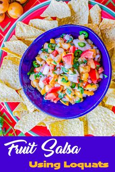 fruit salsa in a blue bowl surrounded by tortilla chips on a red and green plate