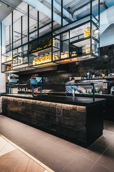 the interior of a restaurant with black counter tops and glass walls, along with lots of food