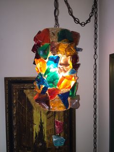 a multicolored light hanging from a chain in a room with a painting on the wall