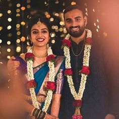 a man and woman standing next to each other in front of a string of lights