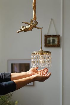 a person holding a chandelier in their hand with a bird hanging from it