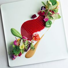 a white plate topped with vegetables on top of a wooden spatula and saucer