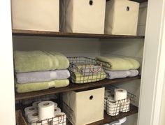 towels and baskets are stacked on shelves in the closet, along with toilet paper rolls