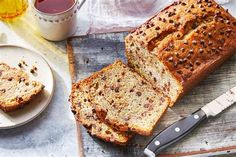 a loaf of bread sitting on top of a cutting board next to a knife and cup