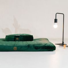 a green bed sitting on top of a white floor next to a lamp and table