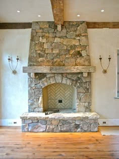 a stone fireplace in the middle of a room with wood flooring and exposed beams