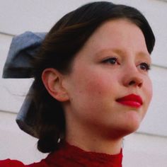 a woman wearing a red dress and a bow in her hair is looking off to the side